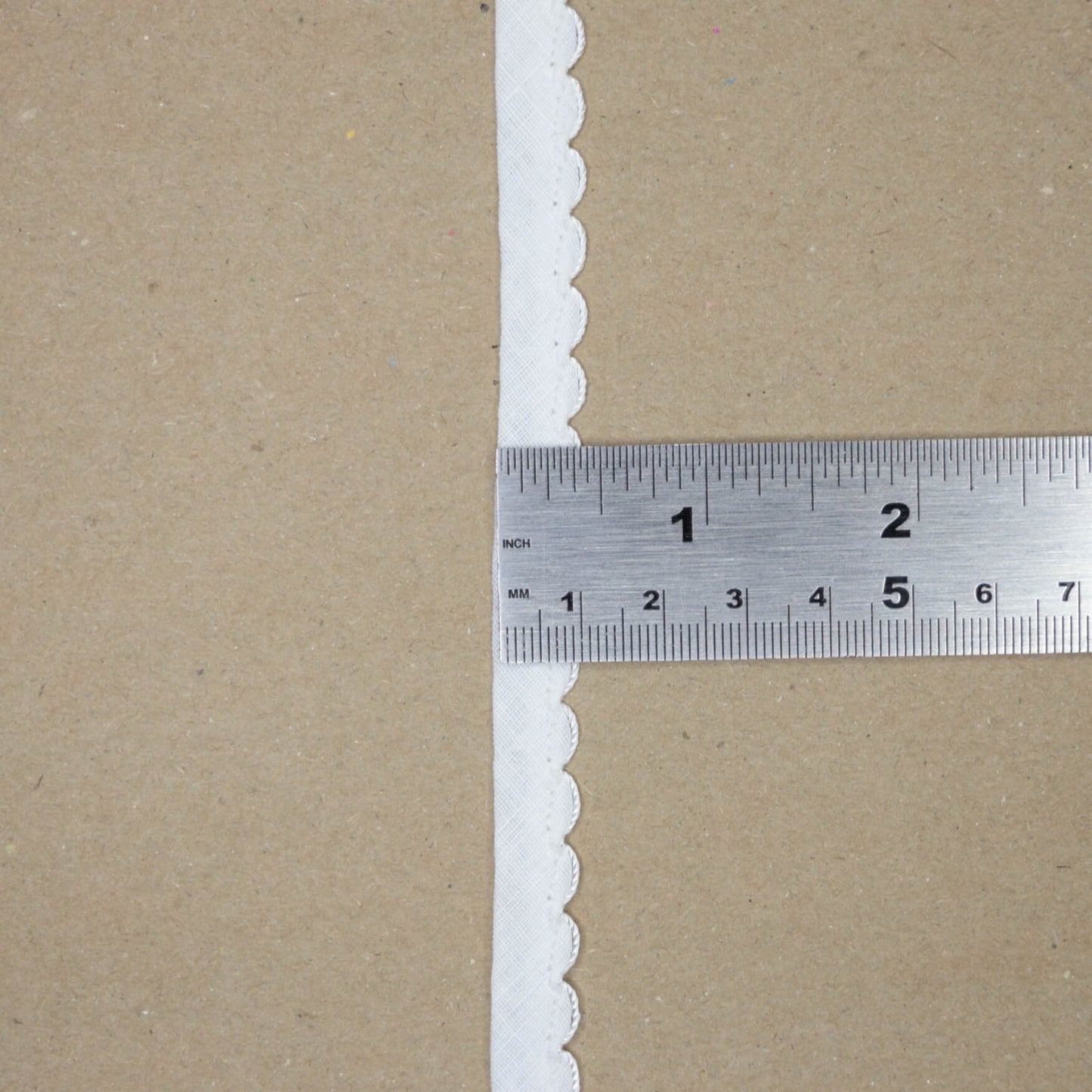 Brown paper with white scalloped edge and a ruler for scale.