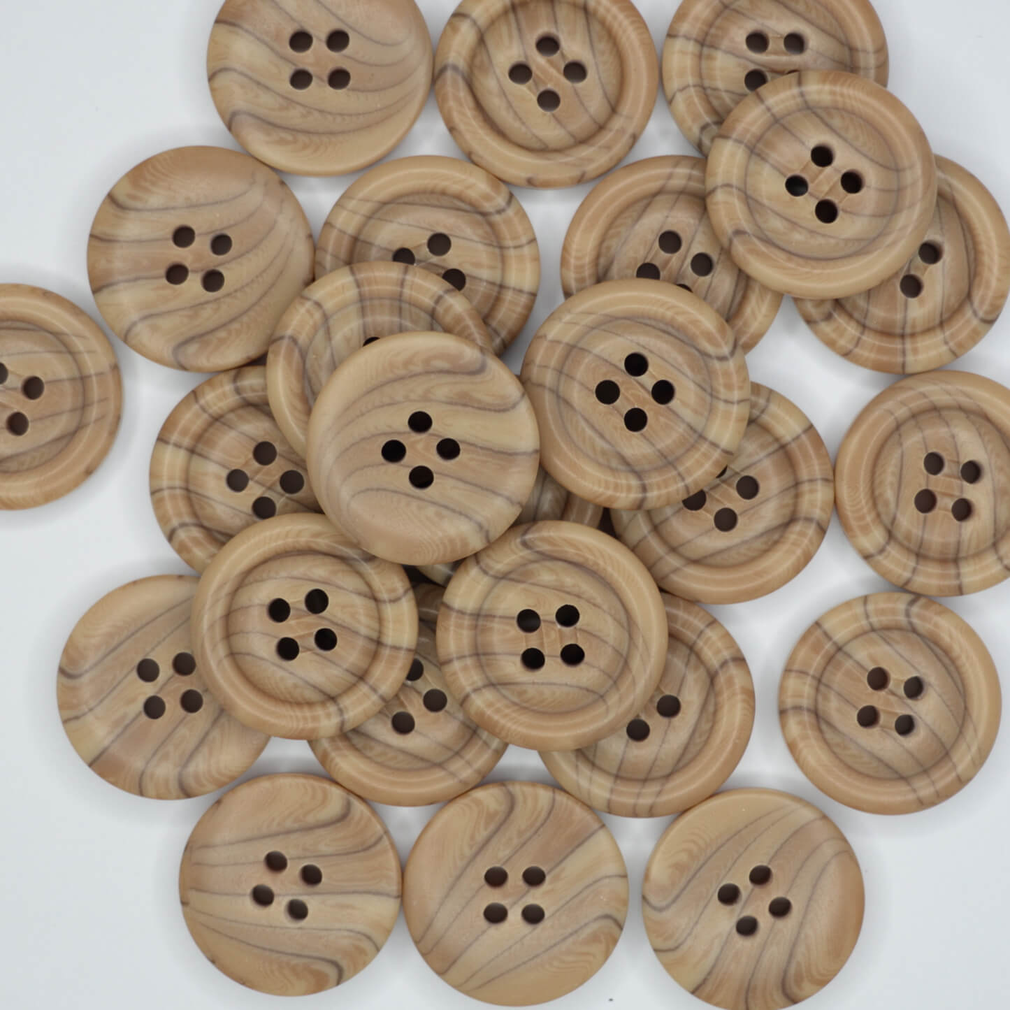 A collection of brown 23mm wooden look 4-hole buttons piled together.