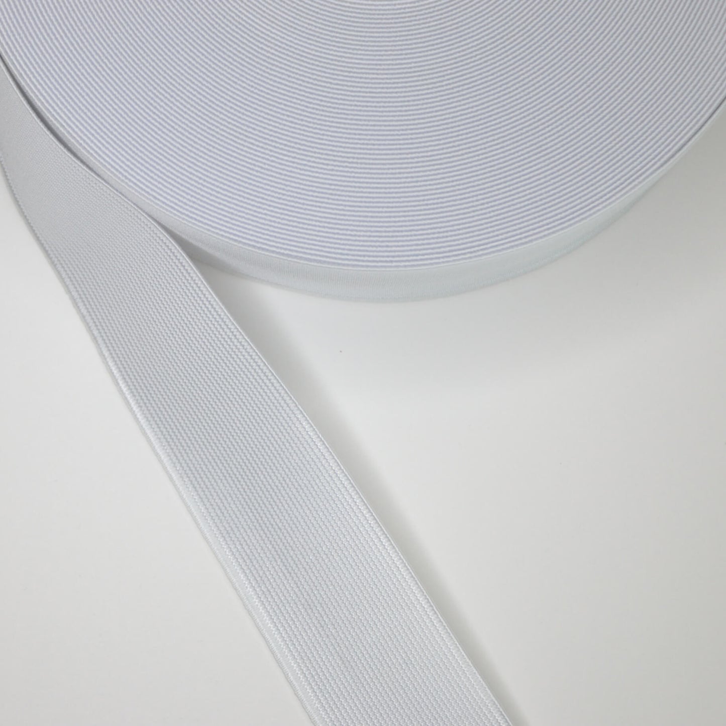A roll of white 38mm elastic band against a white background, designed for use in sewing and crafting projects.