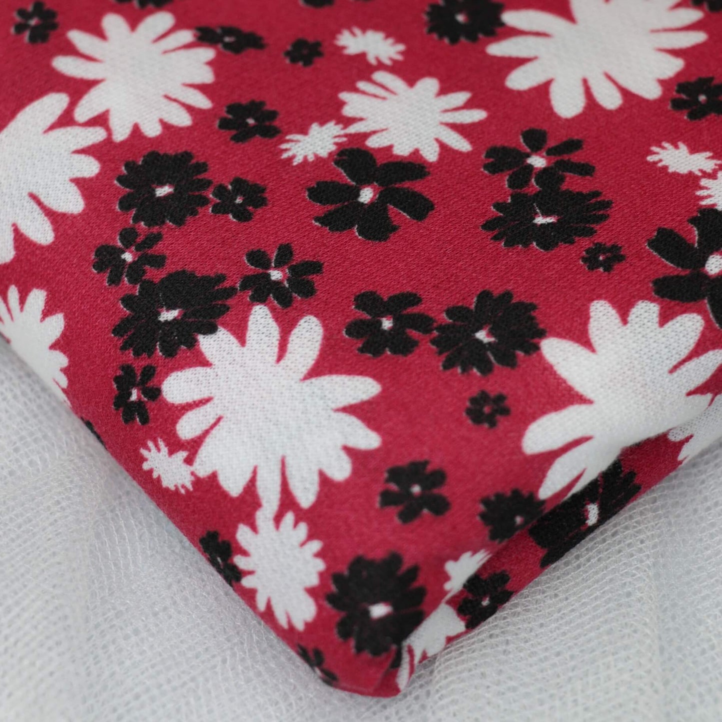 Floral patterned fabric with black and white flowers on a red background