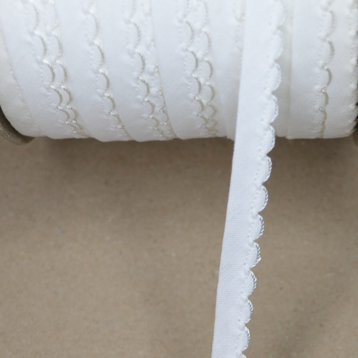 Close-up of a roll of white fabric with textured pattern on a beige background