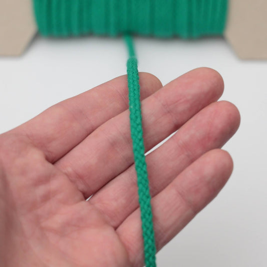 Hand holding a green rope against a white background