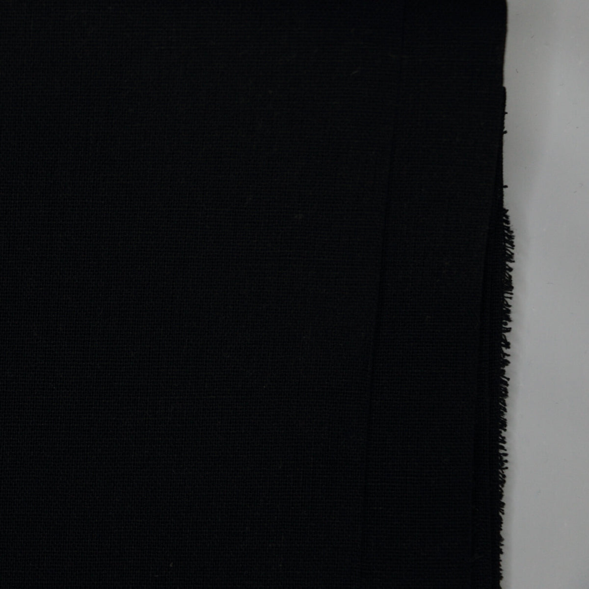 Black fabric with frayed edge on a white background