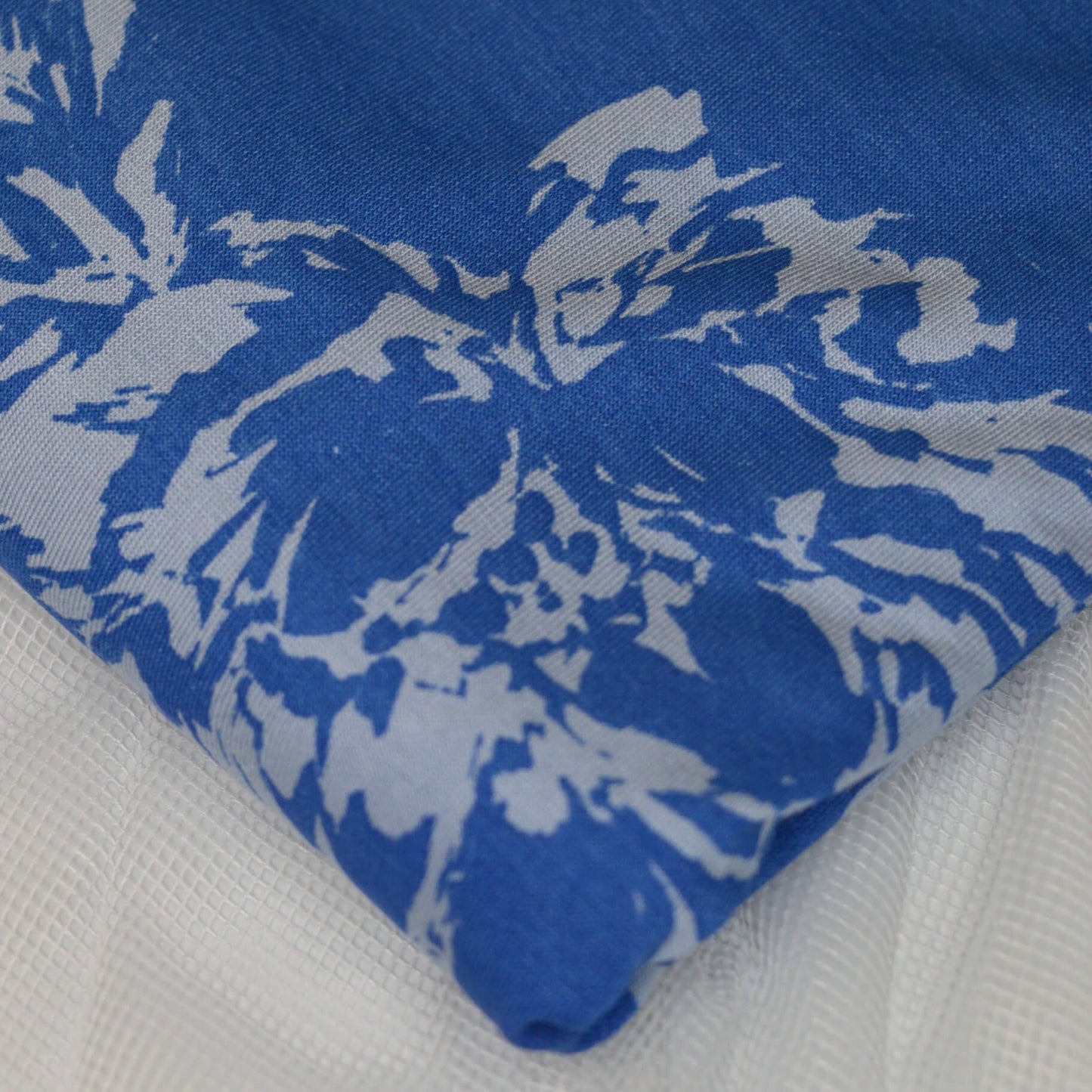 Blue fabric with white floral patterns on a white background