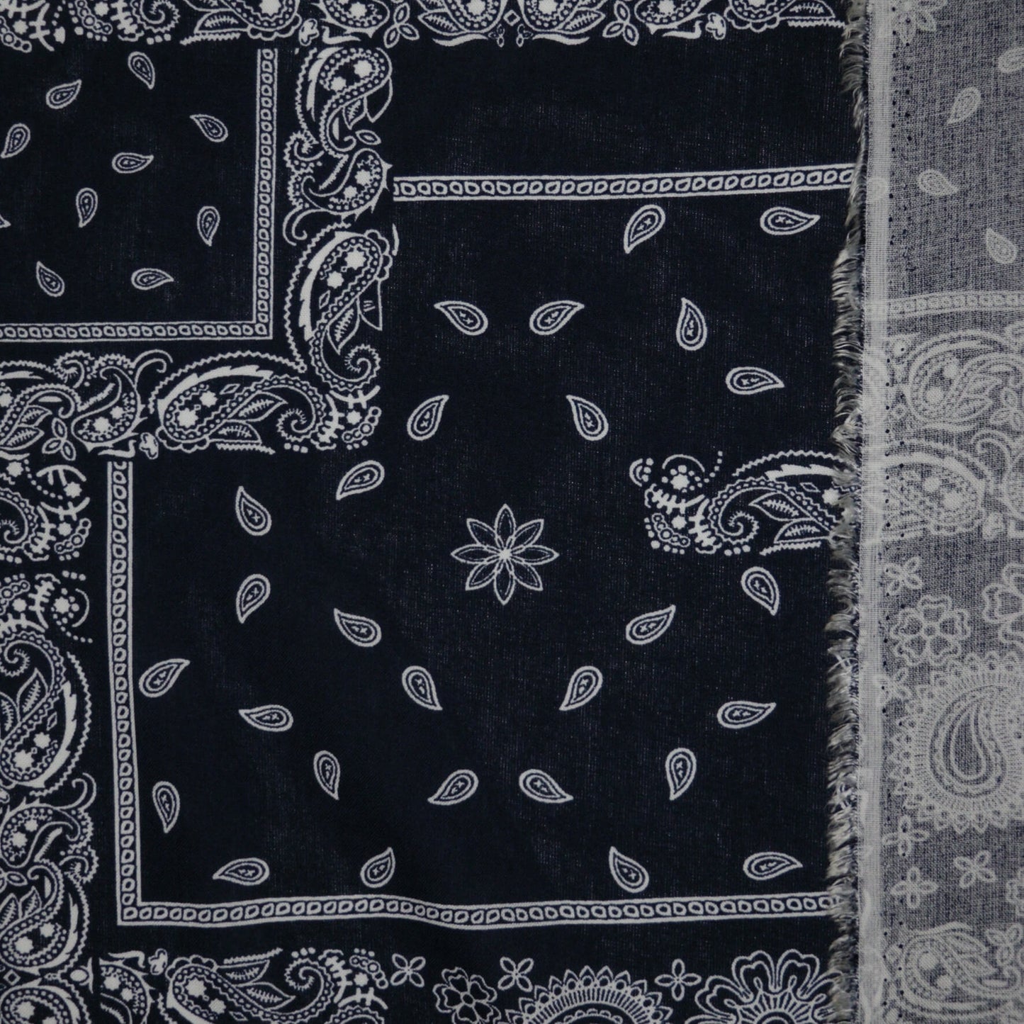 Black bandana with white paisley patterns on a plain background