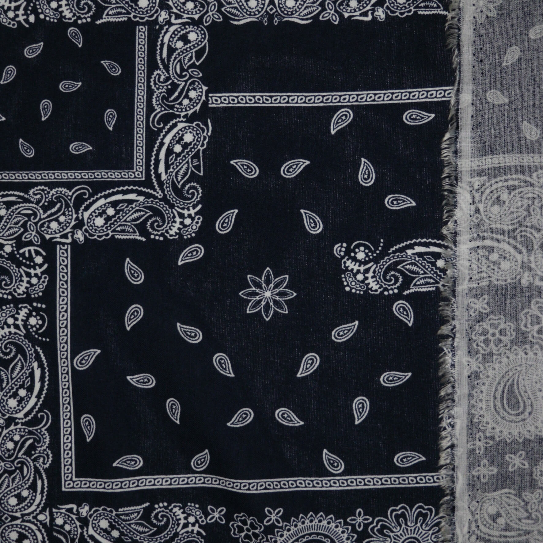 Black bandana with white paisley patterns on a plain background
