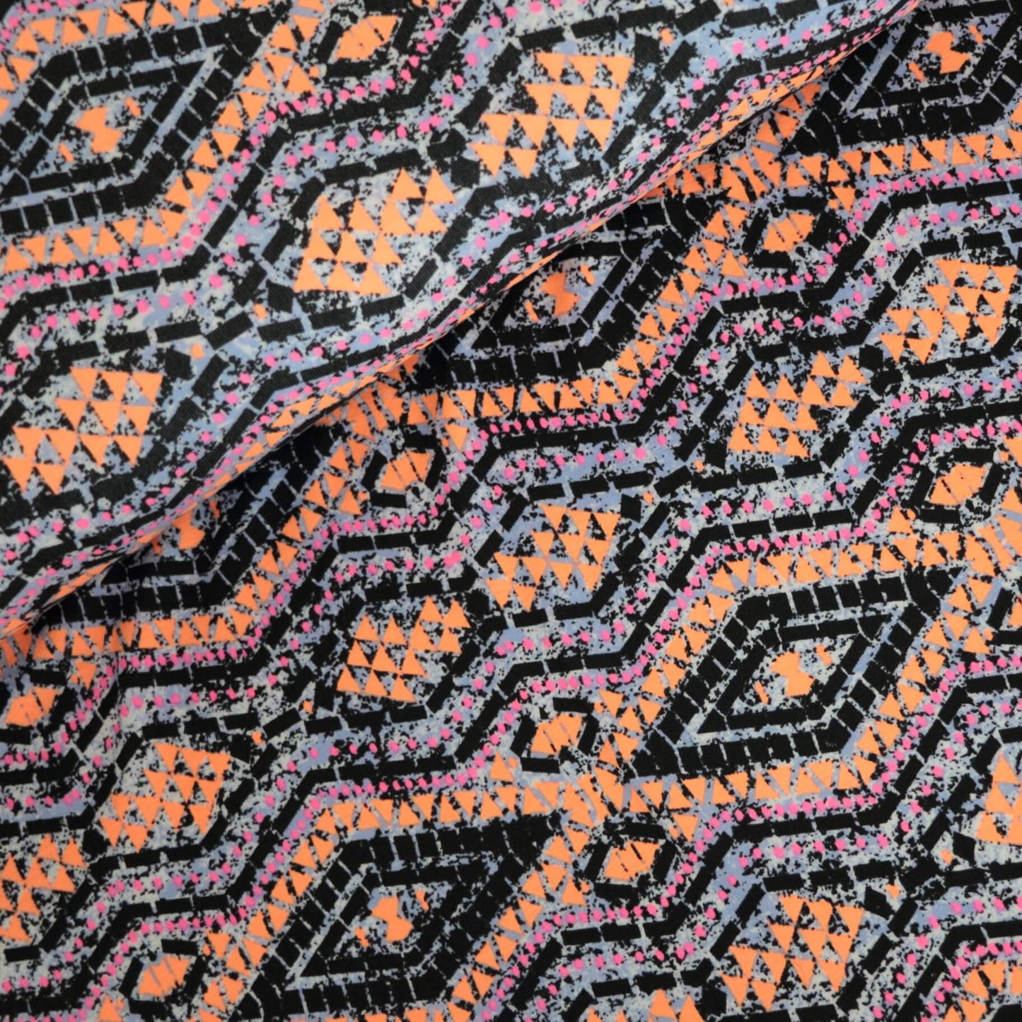 Close-up of a patterned fabric with orange, black, and pink colors.