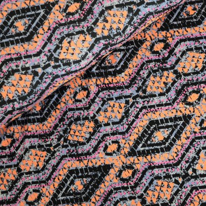 Close-up of a patterned fabric with orange, black, and pink colors.