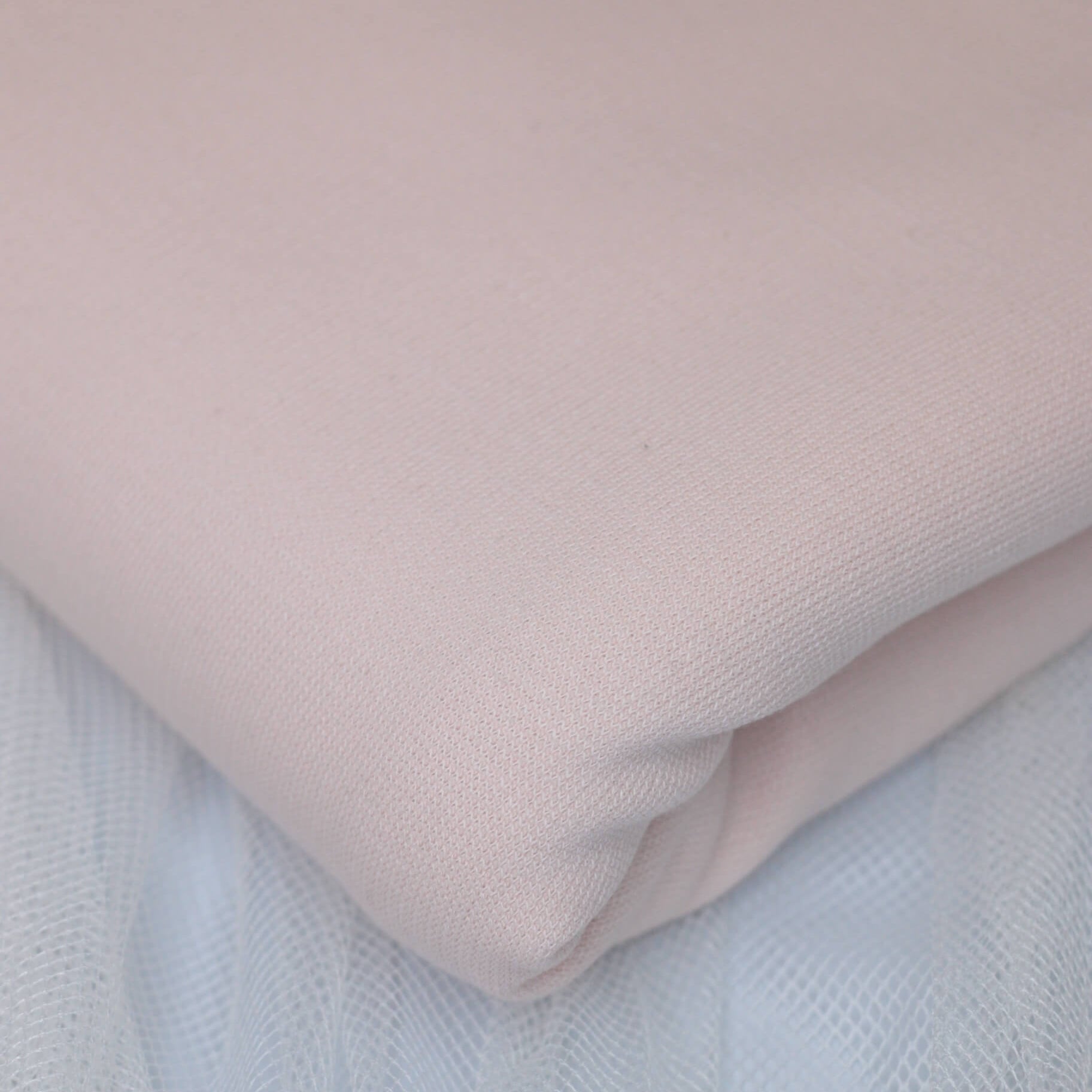 Close-up of a light pink fabric on a textured surface