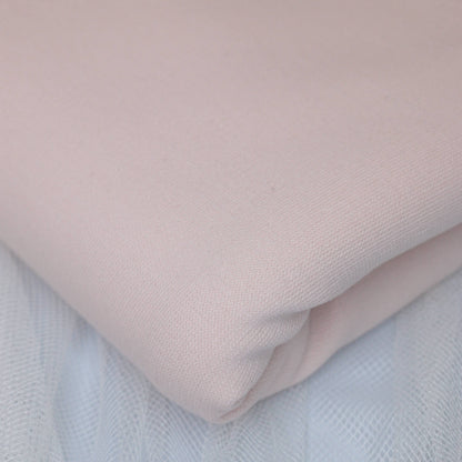 Close-up of a light pink fabric on a textured surface