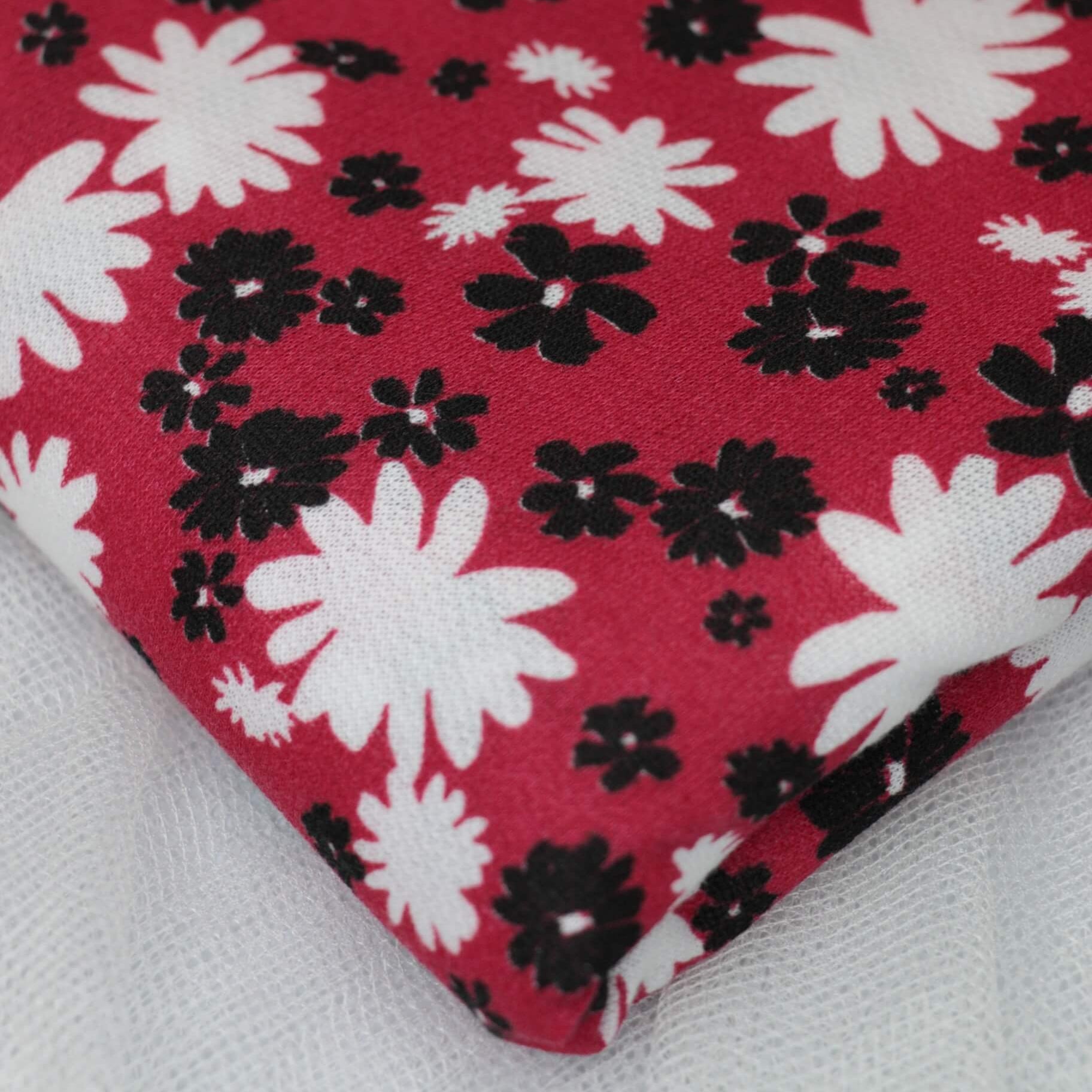 Floral patterned fabric with black and white flowers on a red background