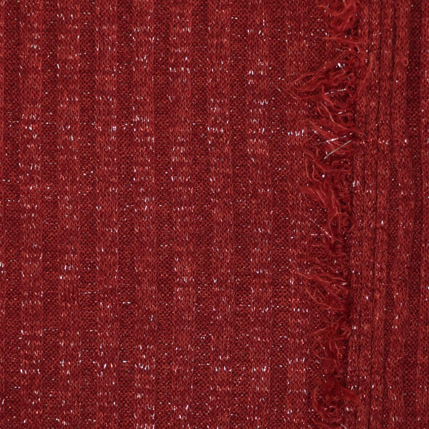 Close-up of red textured fabric with a frayed edge