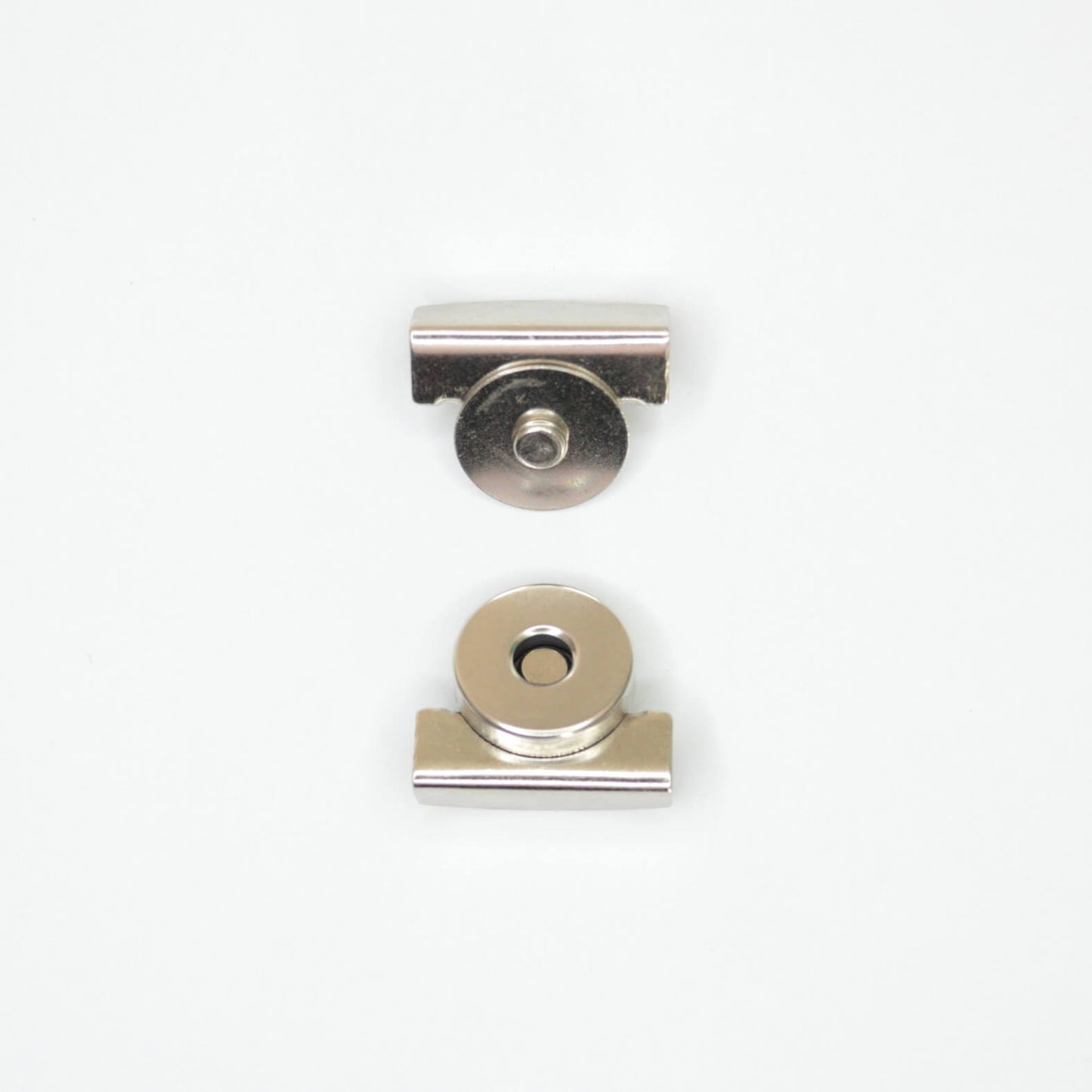 Two small metallic hardware components, magnetic clip parts, shown on a plain white background.