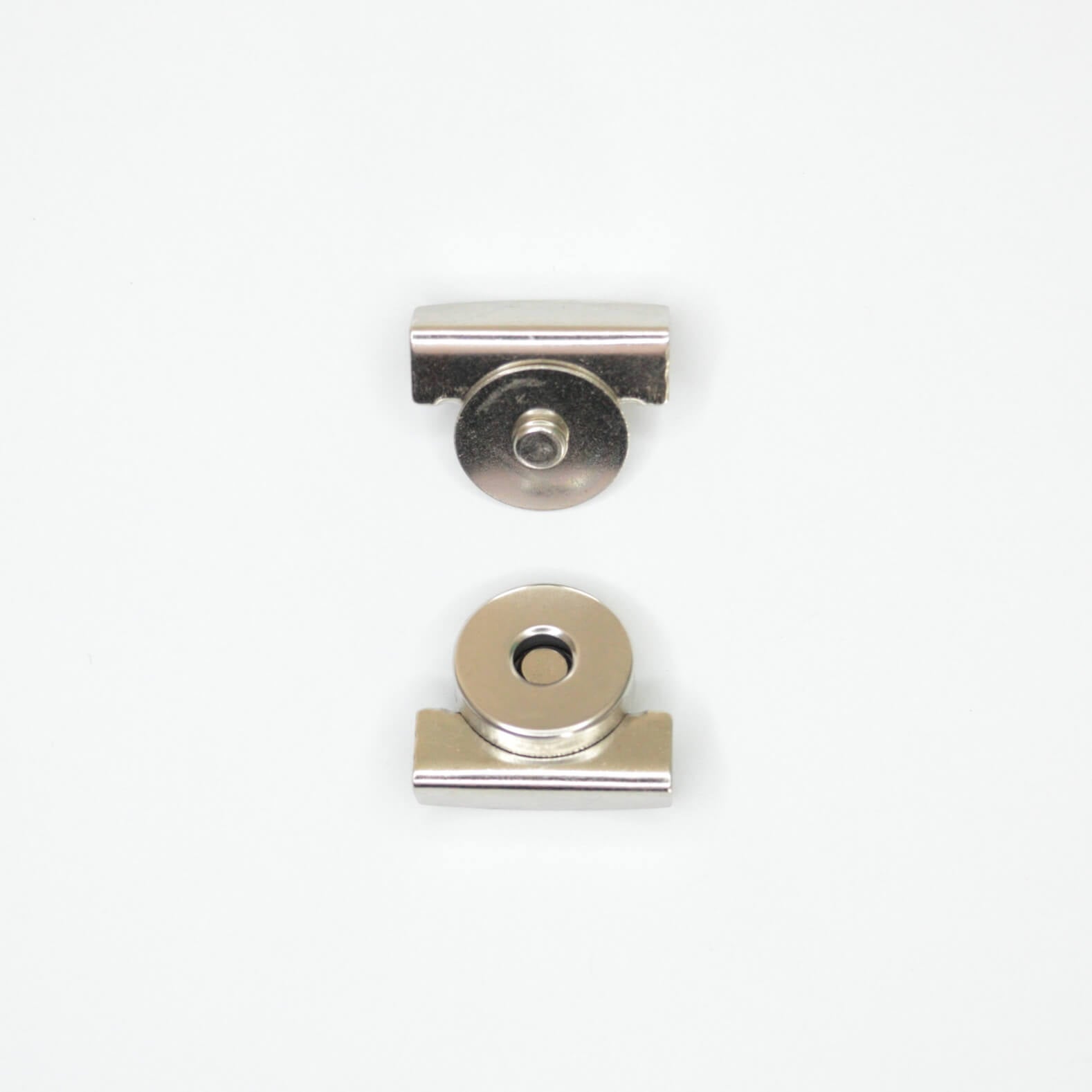 Two small metallic hardware components, magnetic clip parts, shown on a plain white background.