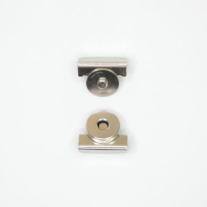 Two small metallic hardware components, magnetic clip parts, shown on a plain white background.