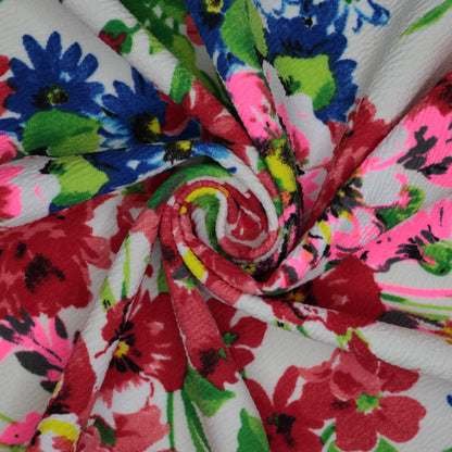 Colorful floral fabric with red, blue, green, and pink flowers on a white background.