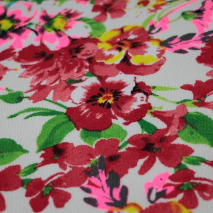 Close-up of a floral fabric pattern with red flowers and green leaves.