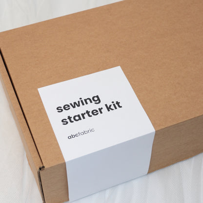 Cardboard box with a white label reading 'sewing starter kit' on a light background